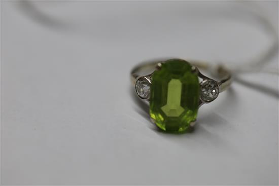 A mid 20th century 9ct white gold and oval cut peridot ring with diamond set shoulders, size M.